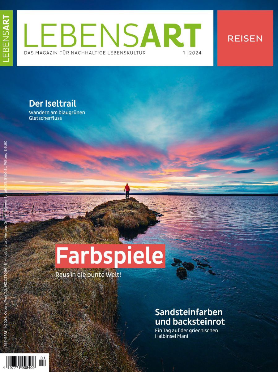 Cover des Magazins. Person steht am Ende einer Landzunge eines Sees und blickt in einen farbenprächtigen Sonnenuntergang.